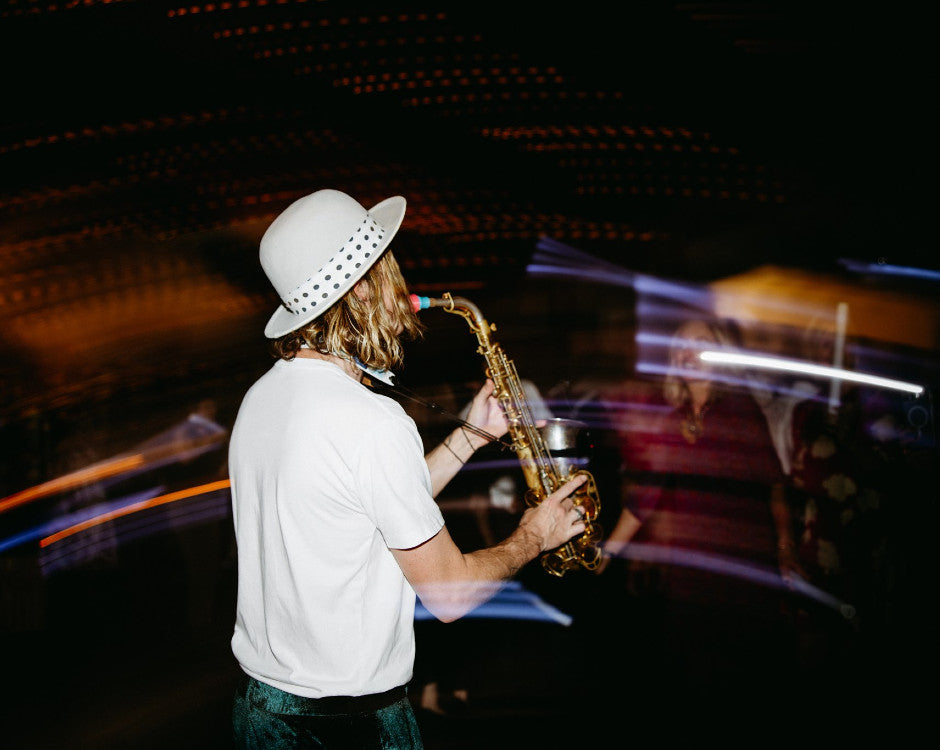 A stylised image of a musician wearing a hat, playing a saxophone on a dance floor.