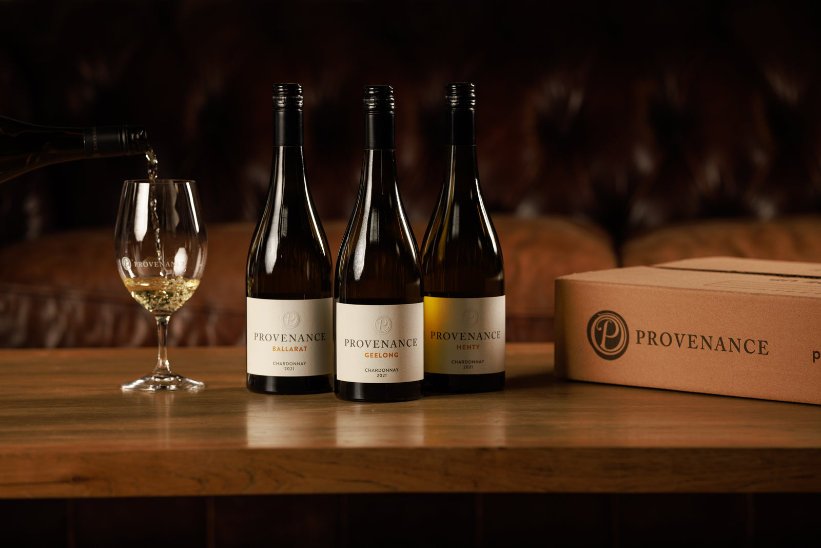 A glass of white wine being poured alongside three bottles of Chardonnay and a carton of wine with the Provenance logo.