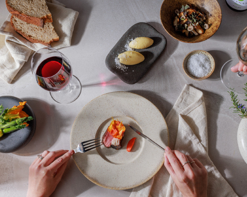 A set table with plates of food and a glass of Pinot Noir.