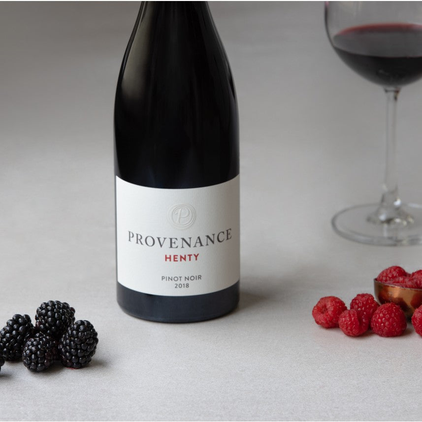 A bottle of Provenance Wines Henty Pinot Noir with a glass of red wine, fresh blackberries and raspberries.