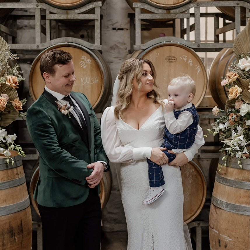 Wedding couple with a child in a wine cellar setting